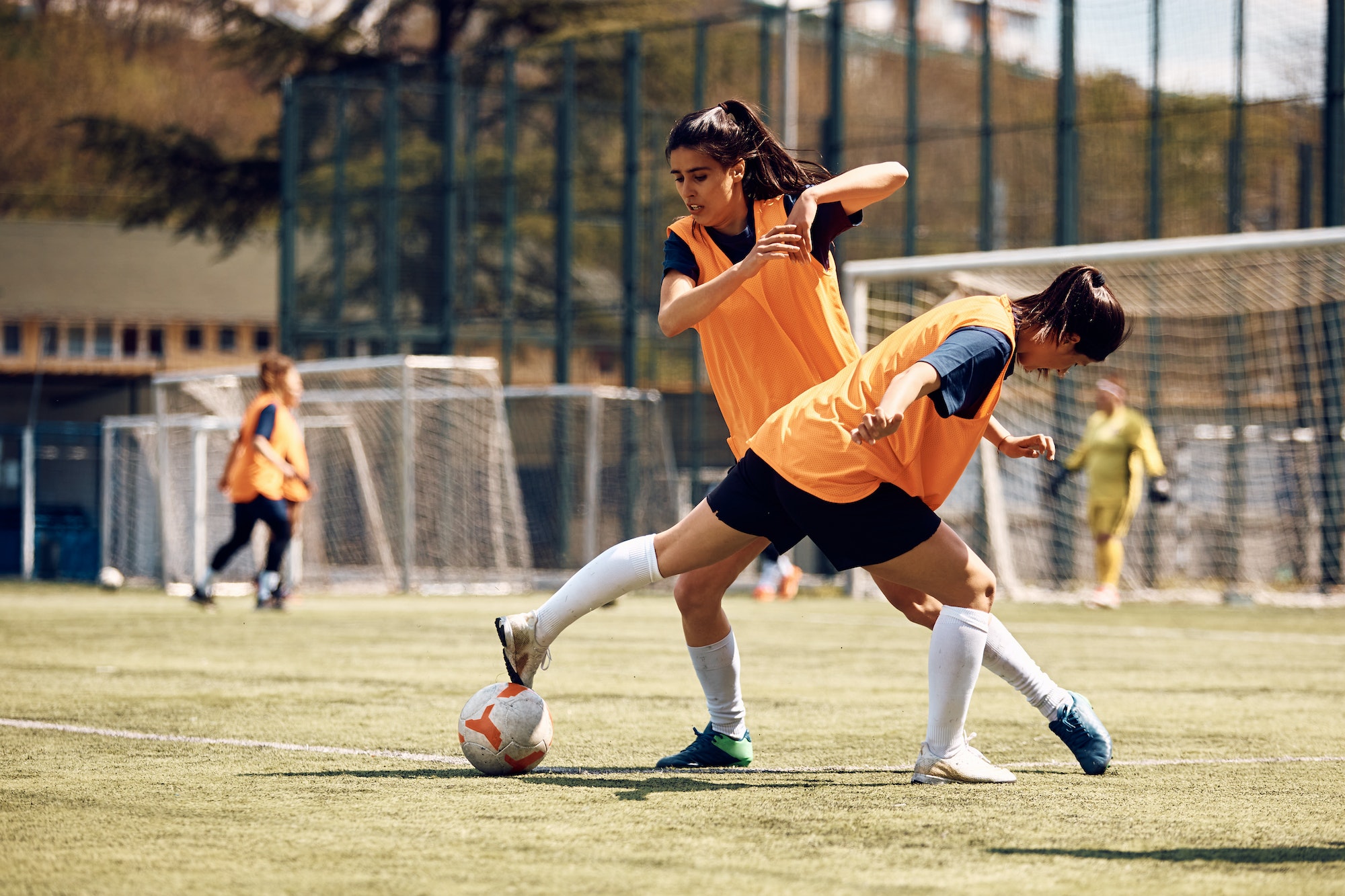 Female players in action on soccer pitch.